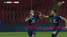 two soccer players wearing hyundai jerseys are celebrating on the field