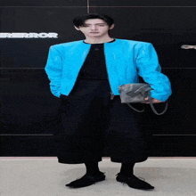 a man wearing a blue jacket and black pants stands in front of a sign that says error