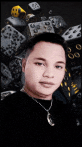 a man wearing a black shirt and a silver necklace stands in front of a pile of dice
