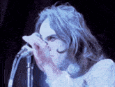 a woman singing into a microphone with a blue background