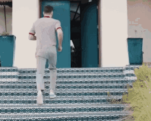 a man walking down a set of stairs with a blue door