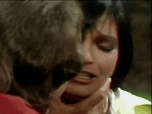 a close up of a woman 's face with a man 's hand touching it