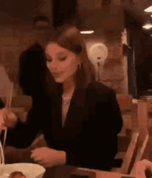 a woman is sitting at a table with chopsticks in a restaurant .