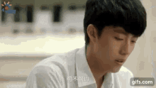 a young man in a white shirt is sitting in a room .