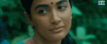 a close up of a woman 's face with a red dot on her forehead and x hk written on the bottom