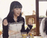 a woman is sitting at a table with a glass of orange juice and a sandwich in her hand .