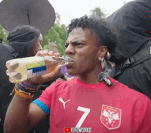a man drinking water from a bottle with the number 7 on it