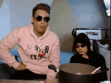 a man wearing a pink hoodie that says u wait txen