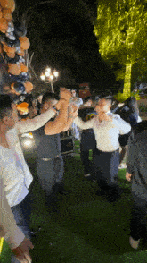 a group of people are dancing in front of balloons and lights