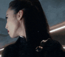 a close up of a woman 's face with her hair in a ponytail and red lipstick .