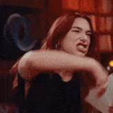a woman with red hair is making a funny face in a bar .