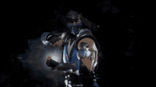a man in a blue costume is standing in the snow with a light coming out of his hand .