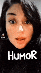 a woman with a nose ring is making a funny face and the word humor is on her face .