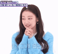 a woman in a blue sweater is smiling with her hands folded