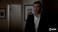 a man in a suit and white shirt is standing in a dark room and says understand