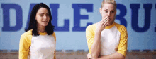 two women are standing next to each other with their arms crossed in front of a sign that says dale .