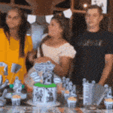 a group of people standing around a table with a cake and cupcakes on it .