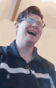 a man wearing glasses is laughing with his mouth open .