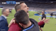a man is hugging another man on a soccer field during a game .