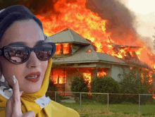 a woman is talking on a phone in front of a burning house