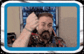 a man with a beard is giving a fist bump in front of a window