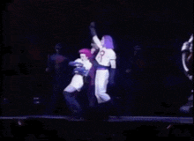 a man and a woman are dancing on a stage with their arms in the air and their shirts have the letter r on them