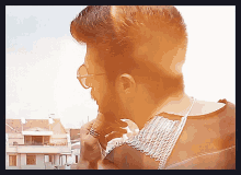 a man wearing sunglasses and a chain around his neck looks at something