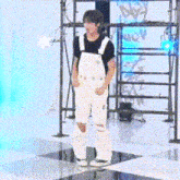 a man in white overalls is standing on a checkered floor in a room .