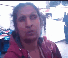 a woman in a red jacket is standing in a crowded area