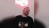 a man wearing a black shirt is standing in front of a red sign that says ' bom ' .