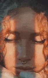 a close up of a woman 's face with a nose ring and red hair .