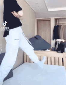 a person is jumping on a bed with their feet up .