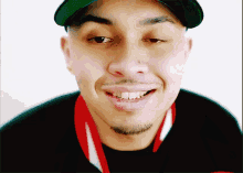 a man wearing a green hat and a black shirt smiles for the camera