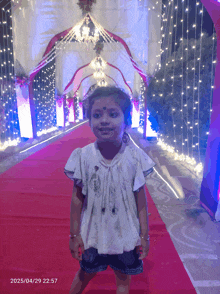 a little girl is standing on a red carpet with the date of 04/29