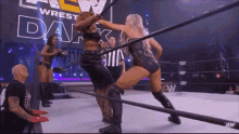 a couple of women are wrestling in a ring with a referee watching .