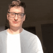 a man wearing glasses and a white shirt is smiling for the camera