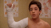 a young boy with a cast on his arm is flexing his arm .