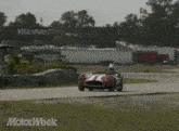a red and white race car is driving on a track with the words motorweek written on the bottom