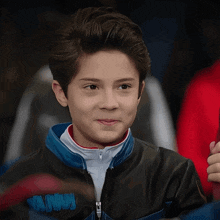 a young boy wearing a black and blue jacket with the word batman on the front
