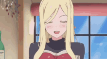 a blonde anime girl is sitting in front of a window holding a book and smiling .