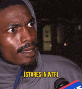 a man in a hooded jacket says [ stares in wtf ] while holding a microphone