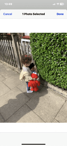 a phone screen shows a picture of two children holding a teddy bear