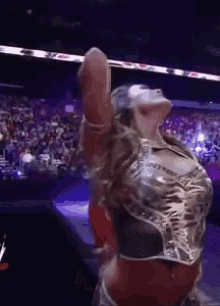 a woman in a metallic top is dancing in a wrestling ring .