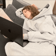 a woman laying on a couch with a laptop