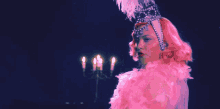 a woman with pink hair is wearing a pink boa and a tiara