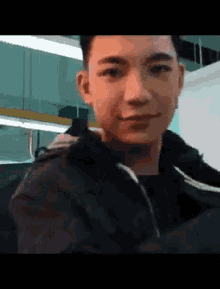 a young man wearing a black jacket is smiling
