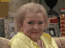 a woman in a yellow sweater is smiling and looking at the camera