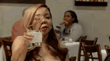 a woman is sitting at a table drinking a glass of water .