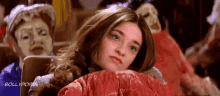 a woman is laying on a couch with a red blanket and a mask in the background .