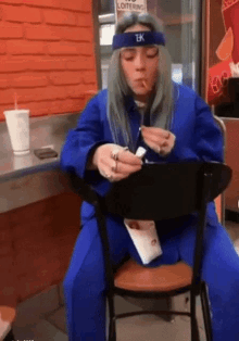 a woman wearing a headband with the letter tk on it is sitting at a table